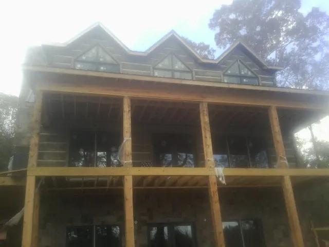 Dormers and porch framing on a large log home under construction — Roof Coating work by our crew in Bunnell