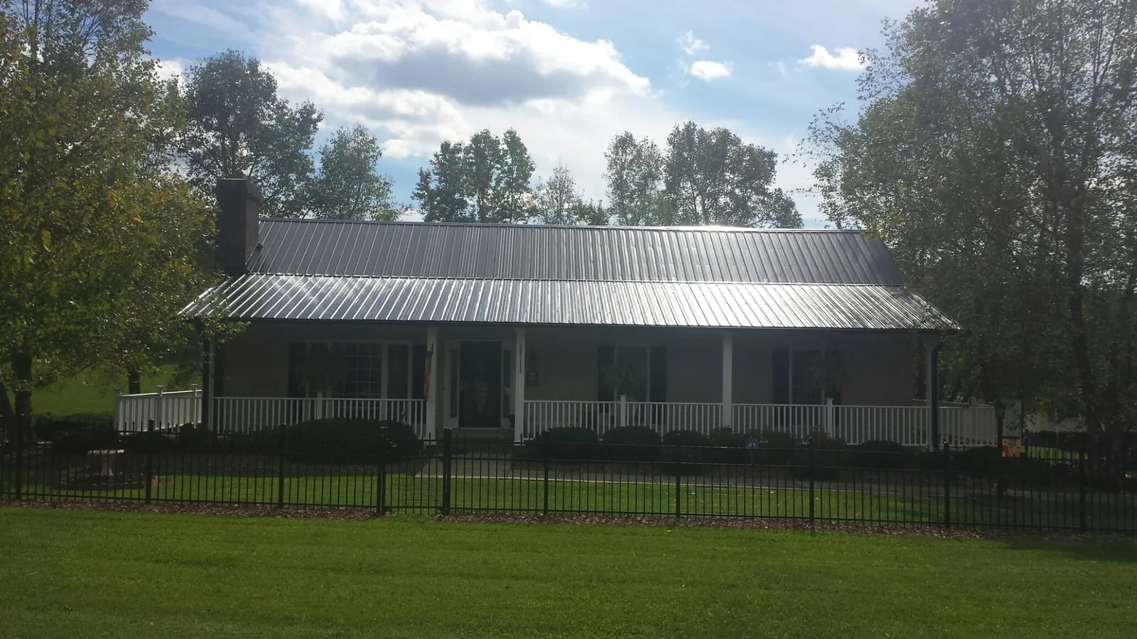 Gray metal roof on a brick ranch with a full width front porch — Gutter Guard Installation work by our crew in Bunnell